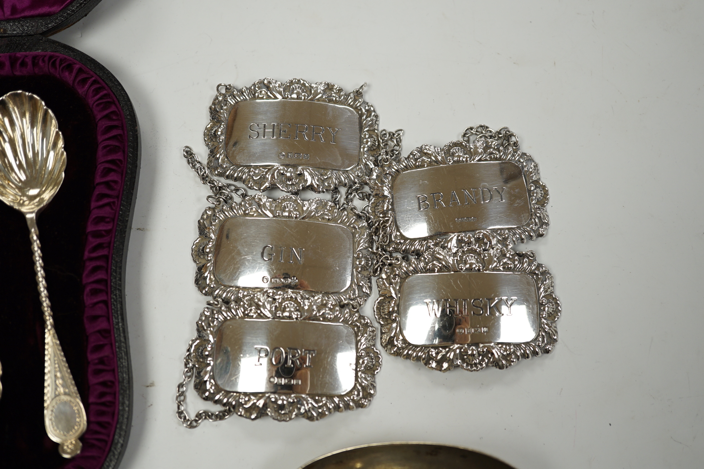 A matched set of five modern silver wine labels, Ray Hall, Sheffield, 1994(3), 1998 & 2000, 61mm, together with two Victorian silver fiddle pattern table spoons, London, 1856 & 1865 and a cased set of six silver coffee s